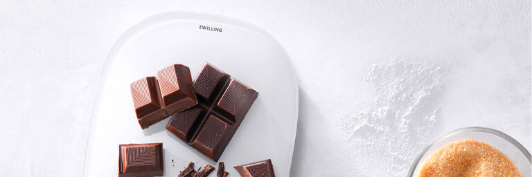 Image of a ZWILLING Digital Kitchen Scale with chocolate being weighed out in a bright kitchen setting.